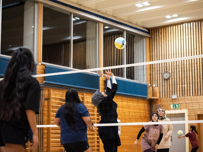 Volleyball_Association_Pervenches woman in white t-shirt and black leggings sitting on blue and yellow floor